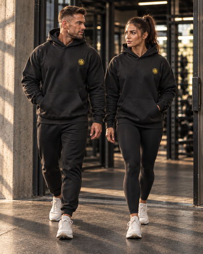 Two models wearing matching black Hack Pro Essential oversized hoodies