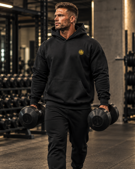 Model holding dumbbells in a black Hack Pro Essential oversized hoodie