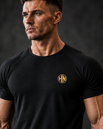Close-up of the neckline and gold chest logo on a black Hack Pro Essential T-shirt