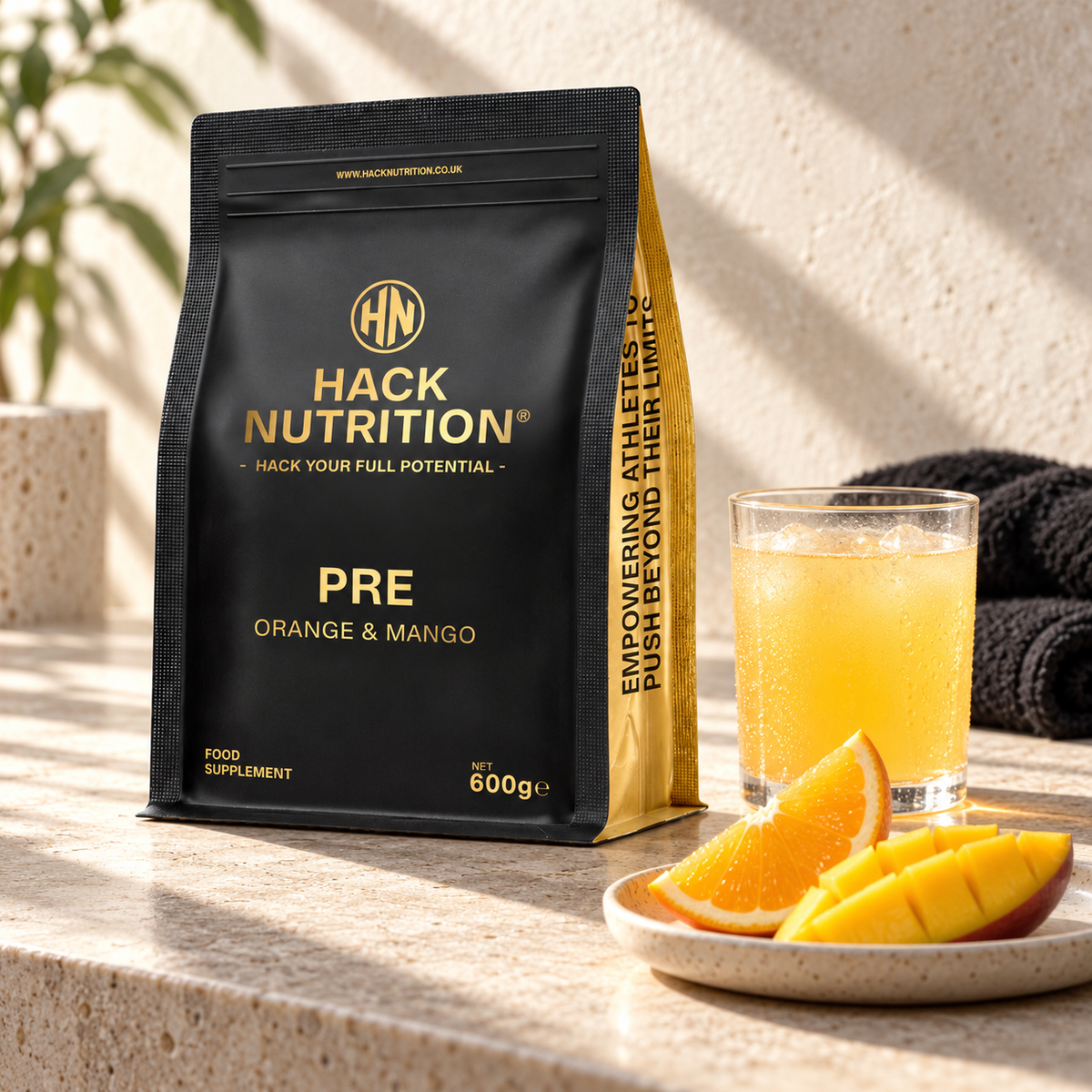 Hack Nutrition PRE pre-workout pouch beside an orange drink and sliced fruit